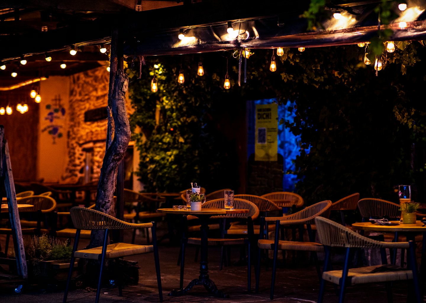 Outdoor restaurant patio with string lights and empty tables.