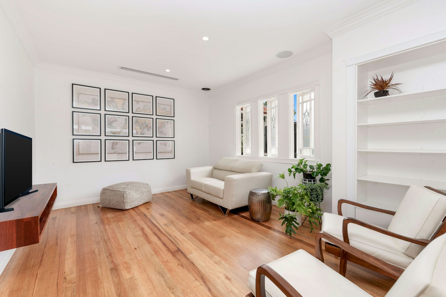 Modern living room with cream sofa, armchairs, and map prints.