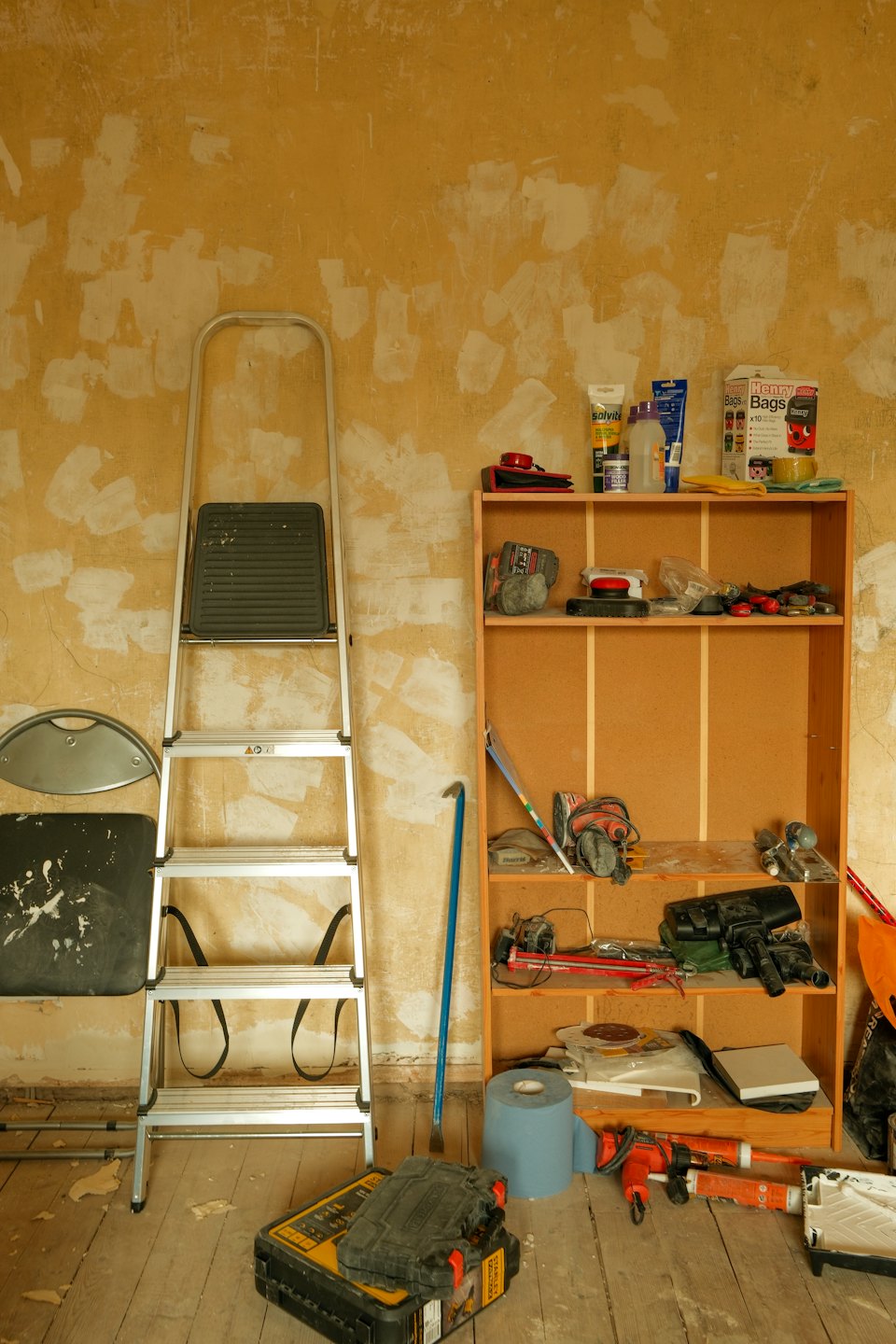 A step ladder and tool shelf in a room undergoing renovation.